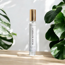 Load image into Gallery viewer, This image features one elegantly designed bottle of Eau De Parfum,with gold cap. and are presented on a wooden surface with large green leaves in the background, enhancing the natural and sophisticated appeal of the products.
