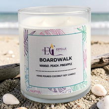 Load image into Gallery viewer, Candle labeled 'Boardwalk' by Estelle on a beach with sand and shells. Mango, peach, pineapple 