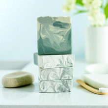 Load image into Gallery viewer, Stack of green and white marbled soap bars on a light surface with a blurred background.  Indulge in our  handmade artisan soap bar that transforms your daily routine into a luxurious escape.
