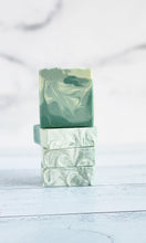 Load image into Gallery viewer, Three green marbled soap bars stacked on a light wooden surface with a white fabric background.
Indulge in our  handmade artisan soap bar that transforms your daily routine into a luxurious escape.
