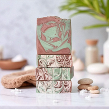 Load image into Gallery viewer, Stack of marbled soap bars on a white surface with a blurred natural background.  Indulge in our  handmadeartisan soap bar that transforms your daily routine into a luxurious escape.
