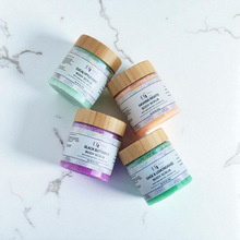 Load image into Gallery viewer, Four jars of body scrubs with wooden lids on a marble surface.Our sugar scrubs are formulated with luxurious ingredients, The sugar granules delicately exfoliate, while the shea butter, sunflower oil, and apricot kernel oil work together to hydrate and moisturize
